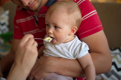 Midsection of parents feeding their baby girl with spoon