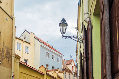 Low angle view of street light amidst buildings against sky