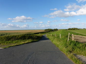 Road amidst field against sky