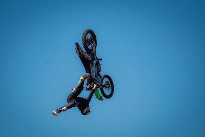 Low angle view of man jumping against clear blue sky