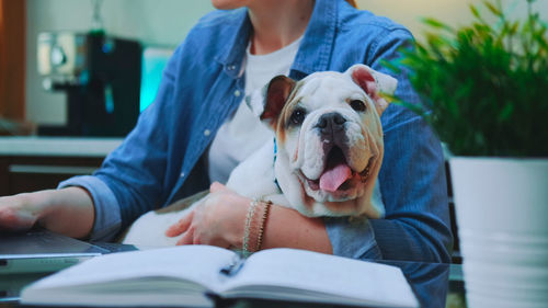 Midsection of woman with dog sitting on book