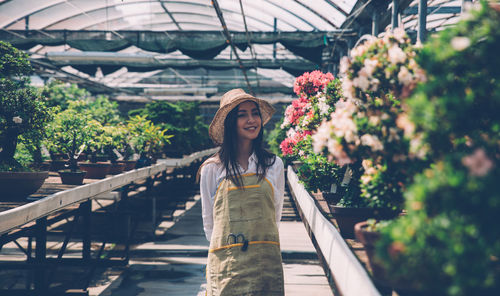 Woman standing by plants in greenhouse