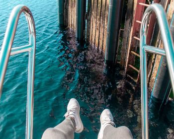 Low section of person wearing shoes against lake