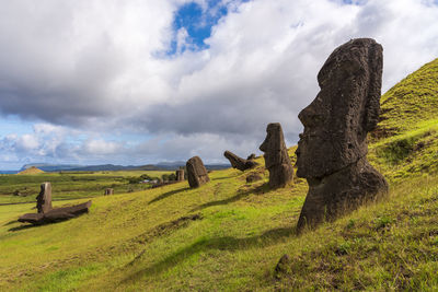 Panoramic view of statues on field against cloudy sky