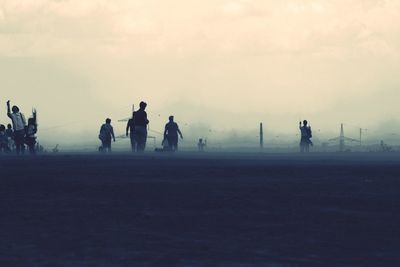 People walking on field in foggy weather