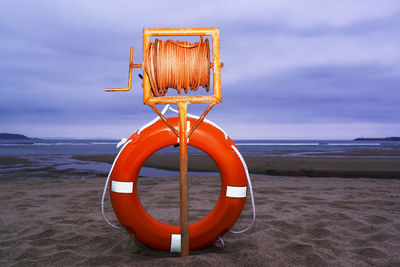 Life belt at beach against cloudy sky during dusk