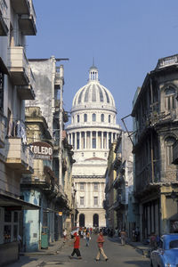 People walking on street amidst buildings against clear sky