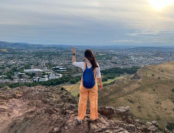 Rear view of woman standing on mountain against sky