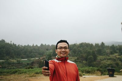 Portrait of smiling young man standing against trees