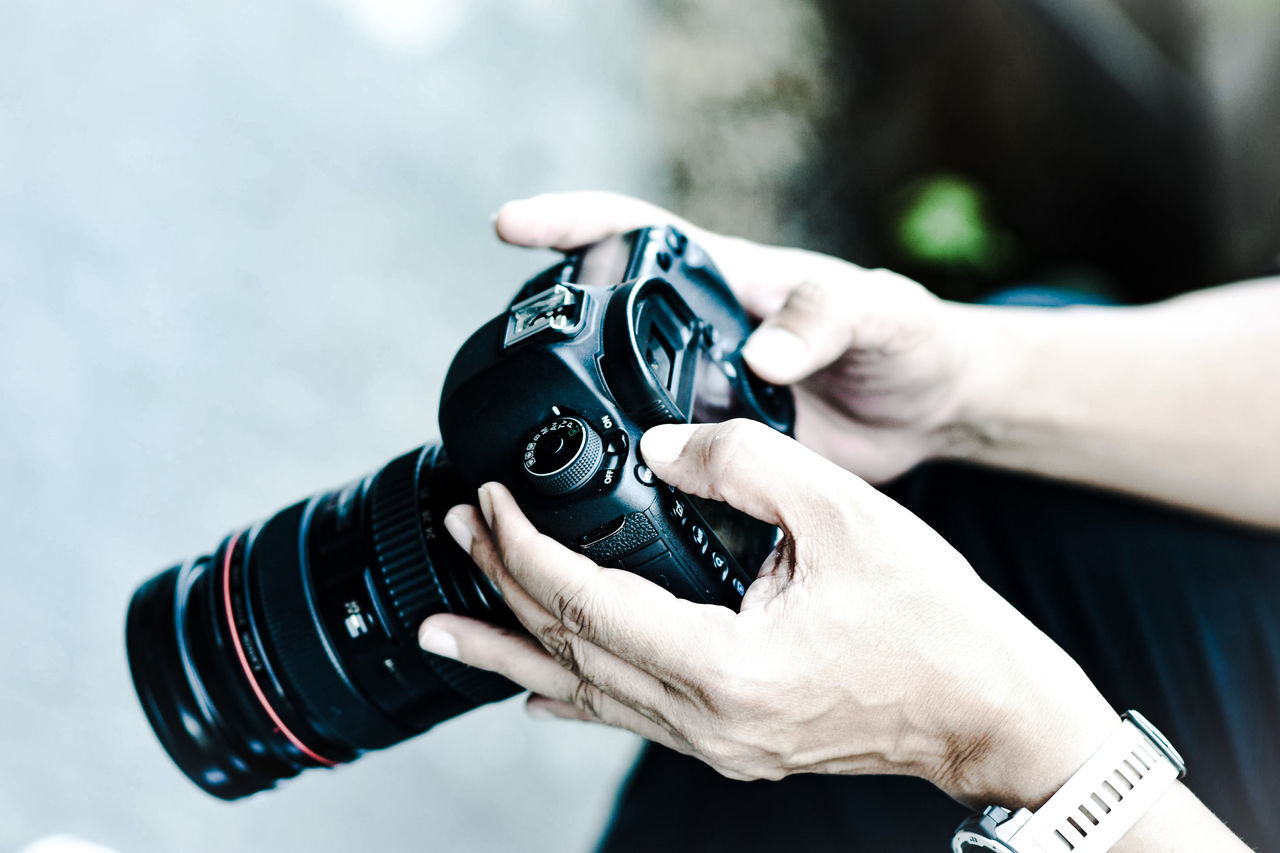 MIDSECTION OF MAN PHOTOGRAPHING CAMERA