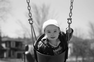 Portrait of boy holding swing in playground