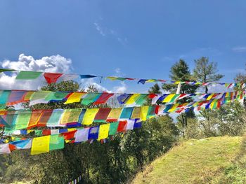 Multi colored flags hanging on clothesline against sky