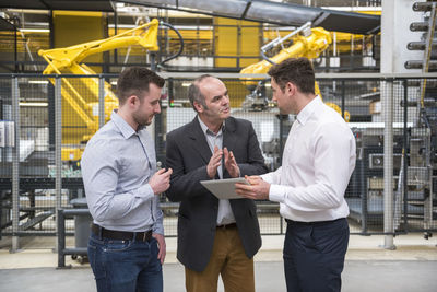 Three men with tablet talking in factory shop floor