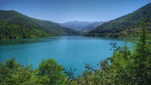 Scenic view of lake and mountains against clear blue sky