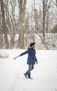Full length side view of woman holding lantern during snowfall