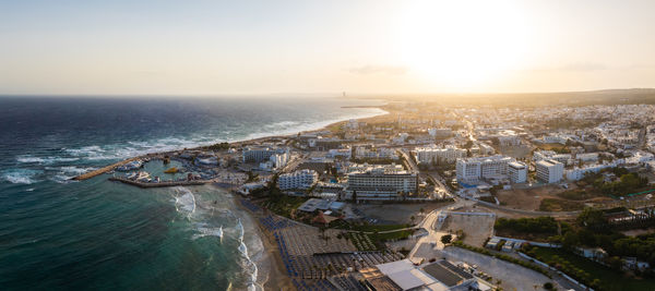 High angle view of townscape by sea against sky during sunset