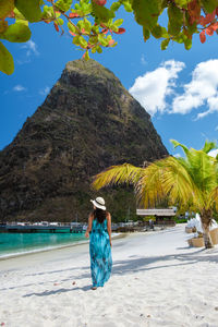 Rear view of woman standing at beach against sky