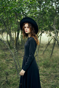 Young woman standing against trees