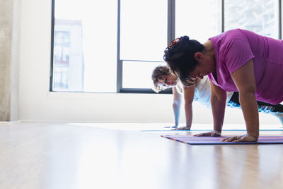 Female friends practicing yoga together in studio