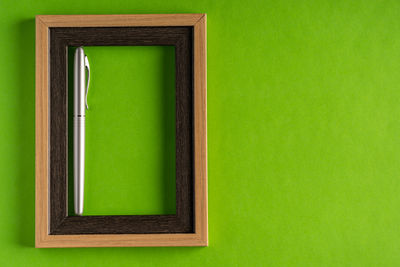 Close-up of open book against green wall