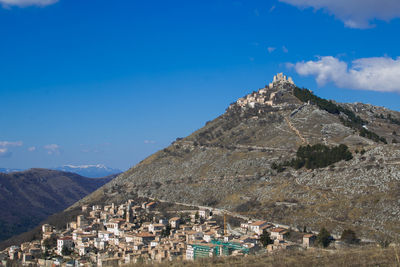 Panoramic view of buildings and mountains against blue sky