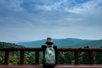 Rear view of man standing by railing against mountain