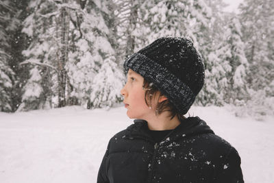 Portrait of woman standing in snow against trees during winter