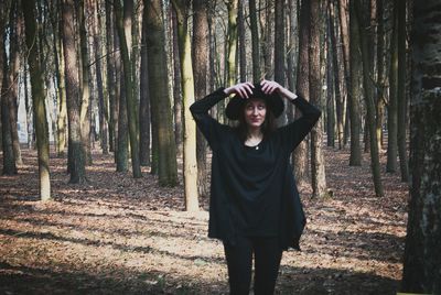 Woman standing by tree trunk in forest