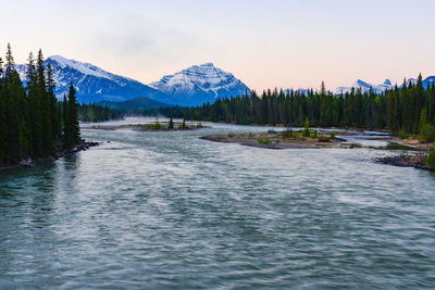 Scenic view of lake by snowcapped mountains against sky