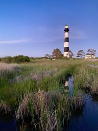 Lighthouse on field against sky