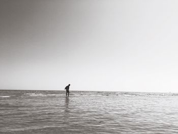 Silhouette man standing in sea against clear sky