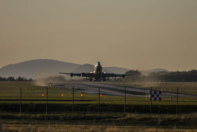 Airplane on airport runway against sky during sunset