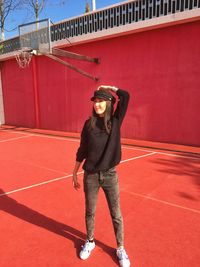 Full length of beautiful young woman standing in basketball court