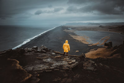 Rear view of man looking at sea against sky