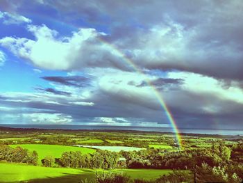 Scenic view of rainbow over field against sky