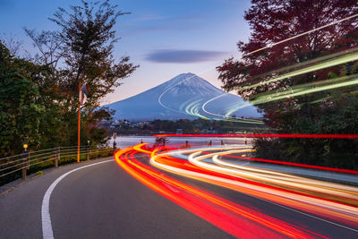Light trails on road by trees against sky at night, fuji mount, japan