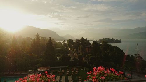 Scenic view of park by lake against cloudy sky at stresa