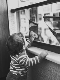 Side view of woman looking through window