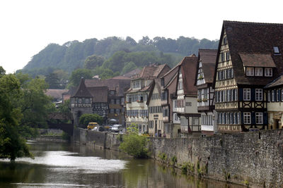 Houses by river and buildings against sky