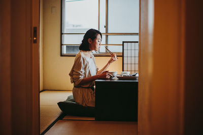 Young woman sitting on table at home