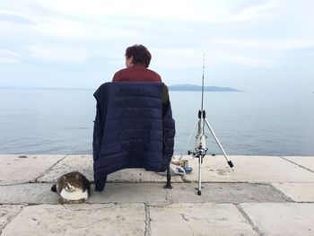 Rear view of lady and cat looking at sea against sky  - catch me if you can