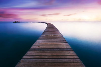 Pier over sea against sky during sunset