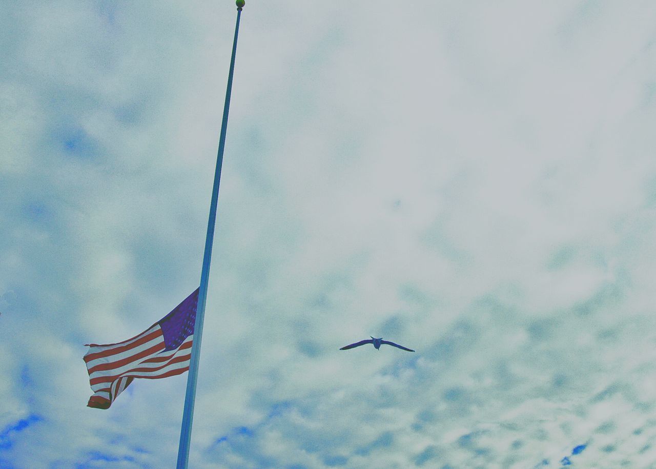 low angle view, sky, cloud - sky, flying, flag, identity, cloudy, patriotism, cloud, national flag, transportation, day, outdoors, blue, no people, mid-air, nature, pole, white color, wind