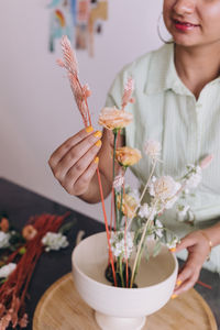 Woman with brow skin tone working in a ikebana centerpiece, working with dried plants 