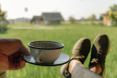 Person hold a coffee with a view of green rice field in concept of relax.