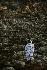 Astronaut standing on land against mountain