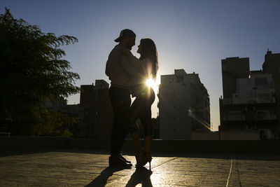 Couple kissing against sky during sunset