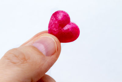 Close-up of hand holding red over white background