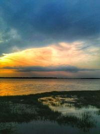 Scenic view of sea against cloudy sky at sunset