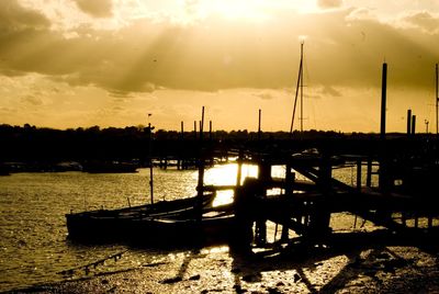 Silhouette sailboats moored in lake against sky during sunset